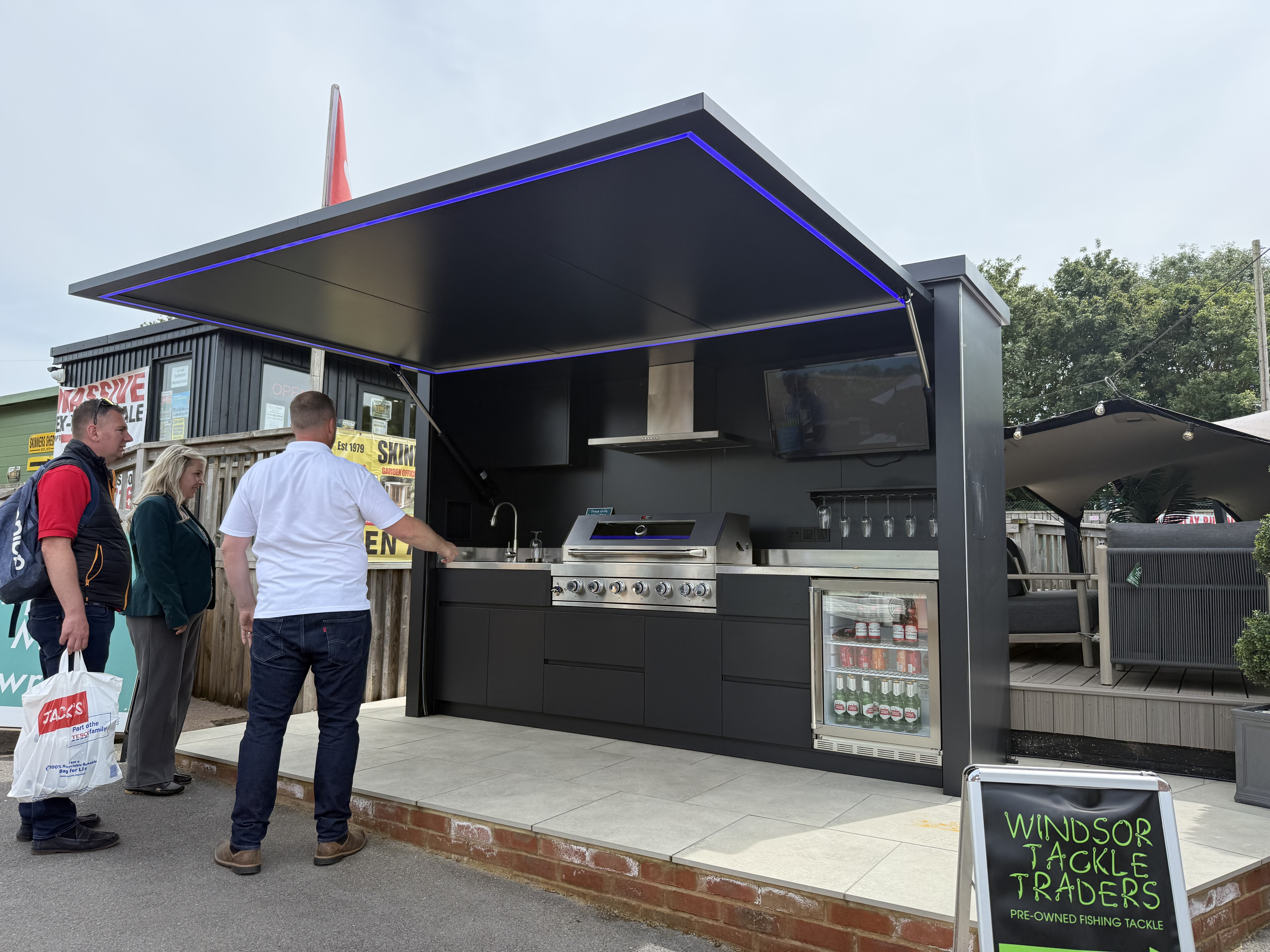 Modern black outdoor kitchen with blue LED lighting and stainless steel grill
